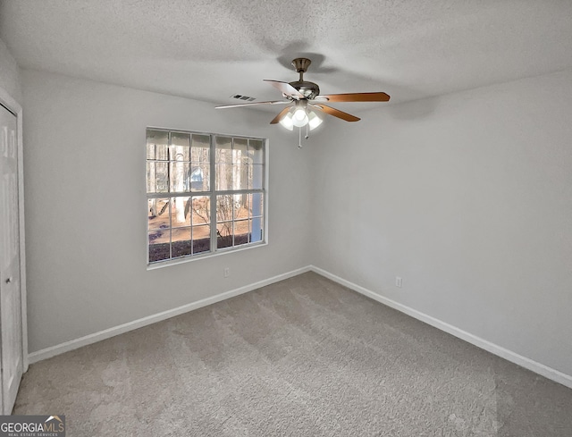 spare room featuring carpet flooring, ceiling fan, and a textured ceiling