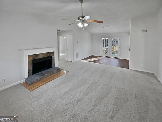 unfurnished living room with ceiling fan, french doors, carpet floors, lofted ceiling, and a fireplace