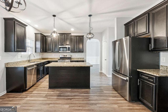 kitchen with dark brown cabinetry, stainless steel appliances, sink, pendant lighting, and a kitchen island