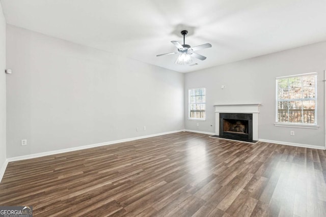 unfurnished living room featuring ceiling fan, plenty of natural light, and dark wood-type flooring