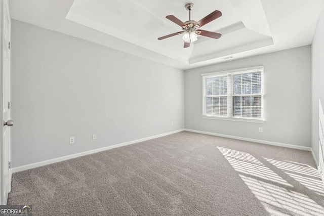 empty room featuring carpet floors, a raised ceiling, and ceiling fan