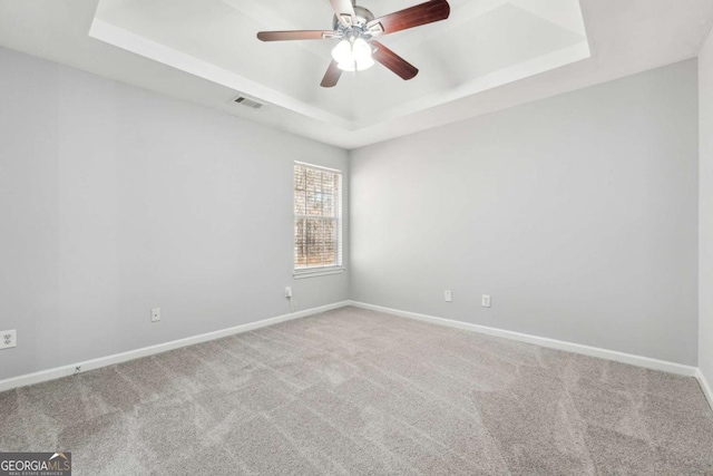 carpeted empty room with a tray ceiling and ceiling fan