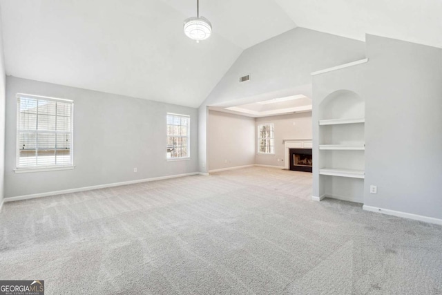 unfurnished living room featuring built in shelves, light colored carpet, and vaulted ceiling