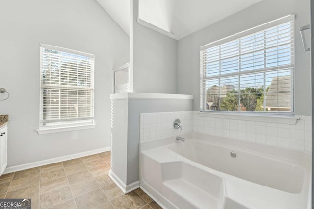 bathroom with vanity, a tub to relax in, vaulted ceiling, and plenty of natural light