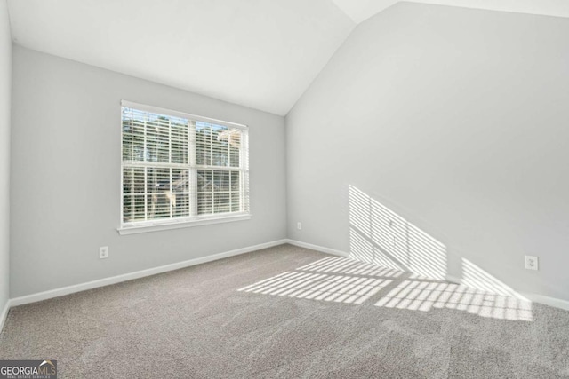 carpeted spare room featuring vaulted ceiling