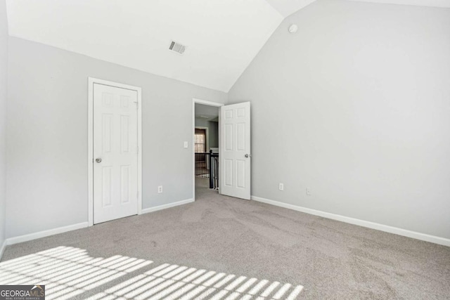 unfurnished bedroom with light colored carpet and vaulted ceiling