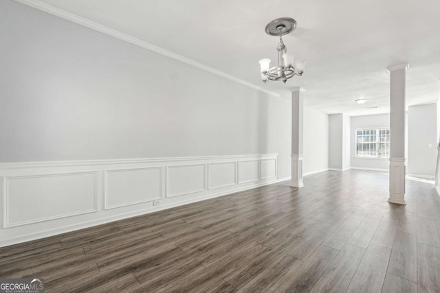 unfurnished room featuring dark hardwood / wood-style floors, ornate columns, crown molding, and a chandelier