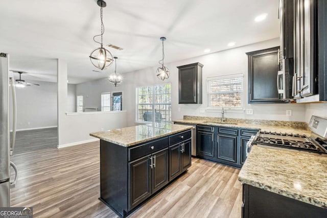 kitchen featuring stove, sink, pendant lighting, light hardwood / wood-style flooring, and a kitchen island