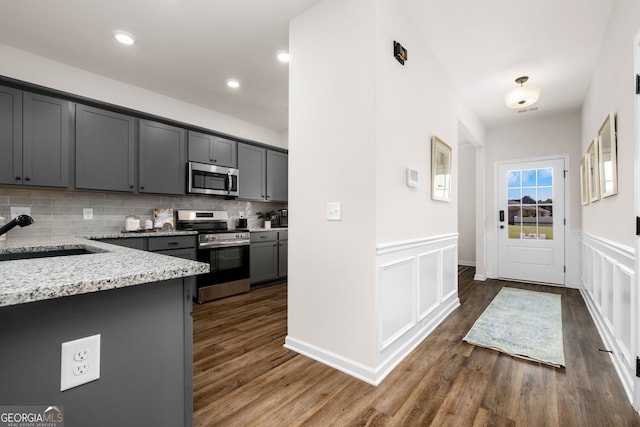 kitchen featuring sink, stainless steel appliances, dark wood-type flooring, light stone counters, and gray cabinets