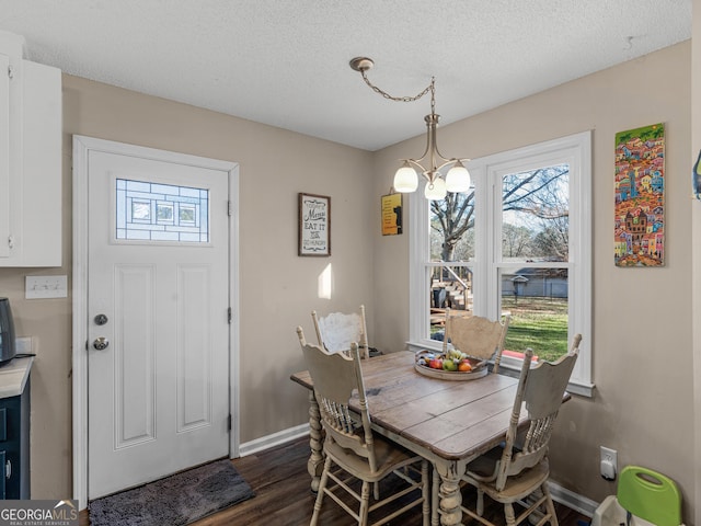 dining area featuring dark hardwood / wood-style floors, a textured ceiling, and a chandelier