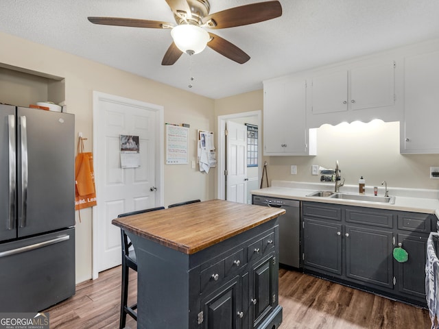 kitchen featuring appliances with stainless steel finishes, dark hardwood / wood-style flooring, sink, white cabinets, and a kitchen island