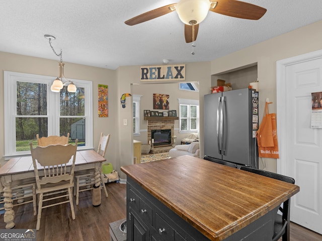 kitchen with stainless steel fridge, a textured ceiling, dark hardwood / wood-style floors, and pendant lighting