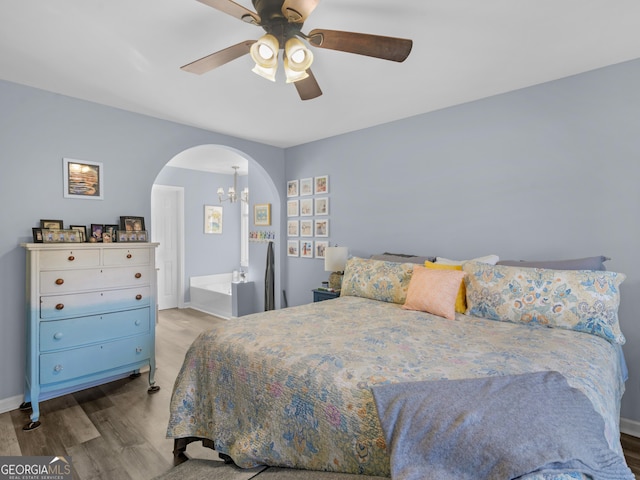 bedroom with light wood-type flooring and ceiling fan with notable chandelier