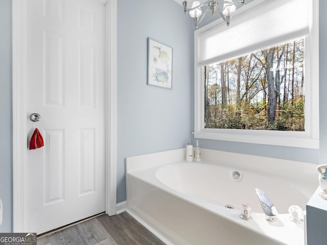 bathroom with hardwood / wood-style flooring, a tub, and a chandelier