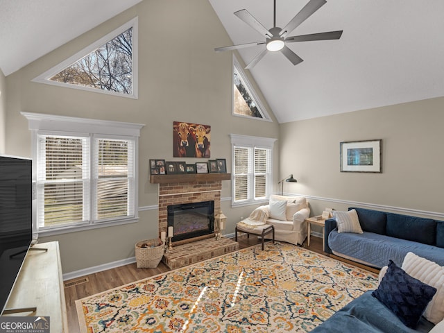 living room featuring a fireplace, ceiling fan, hardwood / wood-style floors, and high vaulted ceiling