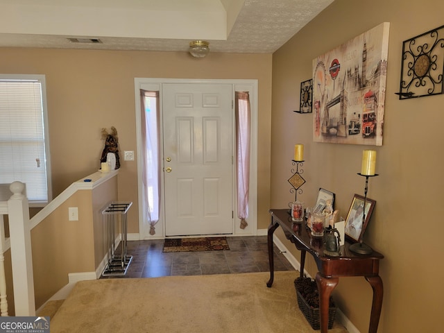 foyer entrance featuring dark tile patterned floors and a textured ceiling