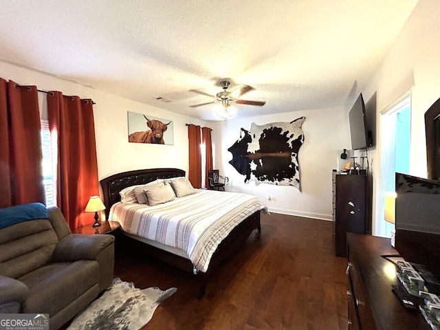 bedroom with ceiling fan, dark hardwood / wood-style floors, a textured ceiling, and multiple windows