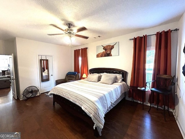 bedroom featuring ceiling fan, dark hardwood / wood-style flooring, and a textured ceiling