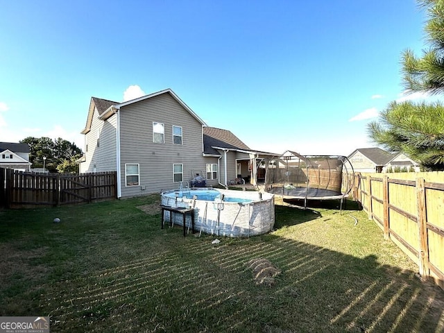 back of property featuring a fenced in pool, a yard, and a trampoline