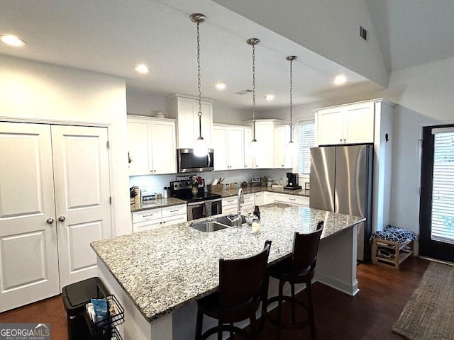 kitchen featuring white cabinetry, sink, hanging light fixtures, stainless steel appliances, and an island with sink