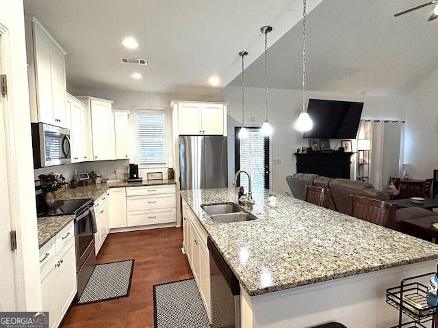 kitchen featuring appliances with stainless steel finishes, a kitchen island with sink, sink, decorative light fixtures, and white cabinetry