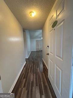 hallway with dark wood-type flooring and a textured ceiling