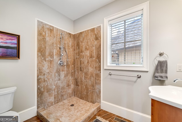 bathroom with tiled shower, vanity, and toilet