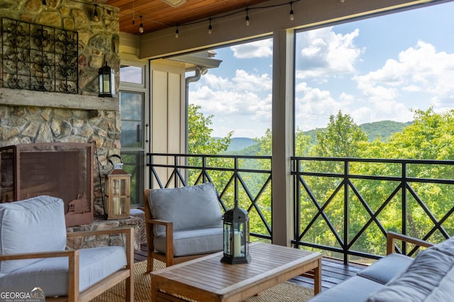 sunroom with an outdoor stone fireplace and wood ceiling