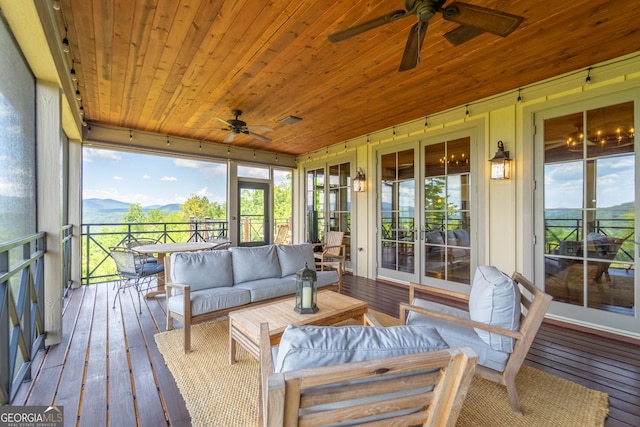 sunroom with a mountain view, ceiling fan, and wood ceiling