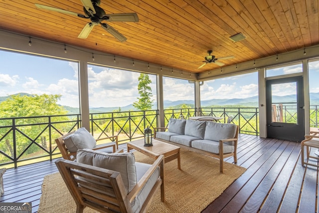 sunroom / solarium featuring a mountain view, ceiling fan, and wooden ceiling