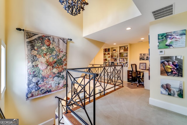 hall with built in features, carpet, and a chandelier