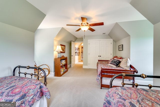 bedroom with light carpet, vaulted ceiling, a closet, and ceiling fan