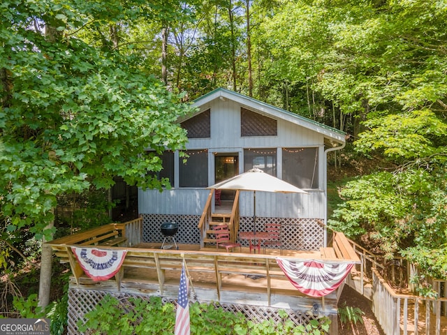 wooden deck with a grill and a sunroom