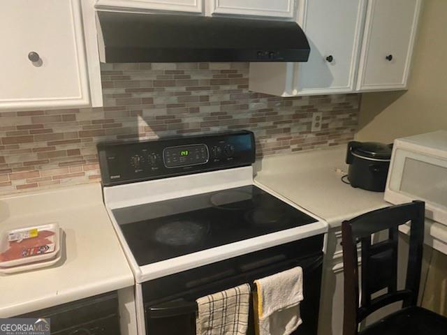 kitchen with backsplash, white cabinets, and white appliances