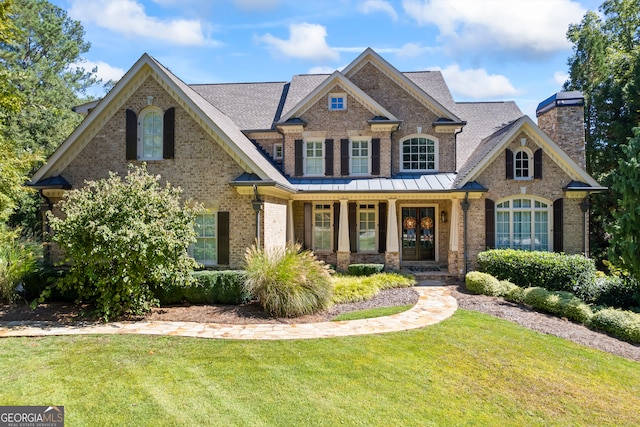 craftsman-style home with a front lawn, a porch, brick siding, and a chimney