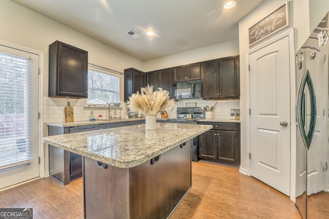 kitchen with dark brown cabinetry, visible vents, appliances with stainless steel finishes, a breakfast bar area, and a center island