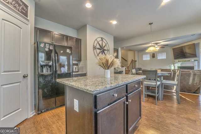 kitchen with a kitchen island, black refrigerator with ice dispenser, dark brown cabinets, and open floor plan