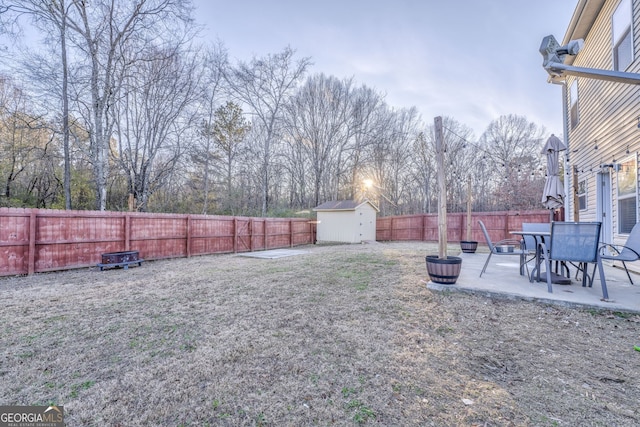 view of yard with a fenced backyard, an outdoor structure, a storage shed, and a patio