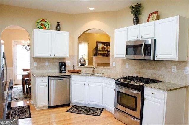 kitchen with white cabinets, appliances with stainless steel finishes, decorative backsplash, and sink