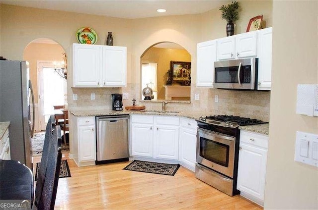 kitchen featuring backsplash, stainless steel appliances, white cabinetry, and sink