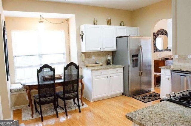 kitchen featuring appliances with stainless steel finishes, backsplash, light hardwood / wood-style floors, and white cabinetry