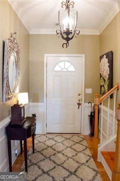 entrance foyer with crown molding, plenty of natural light, and an inviting chandelier