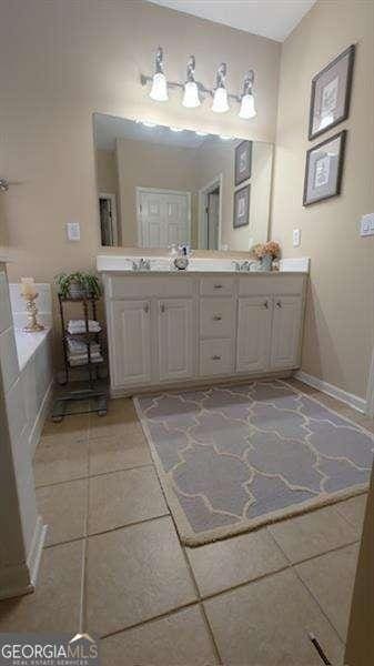 bathroom featuring tile patterned flooring, vanity, and a tub