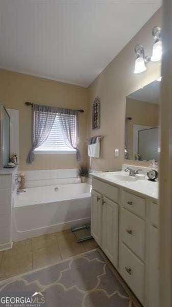 bathroom featuring a washtub, vanity, and tile patterned flooring