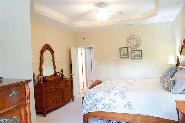 bedroom with a tray ceiling, ceiling fan, and light carpet