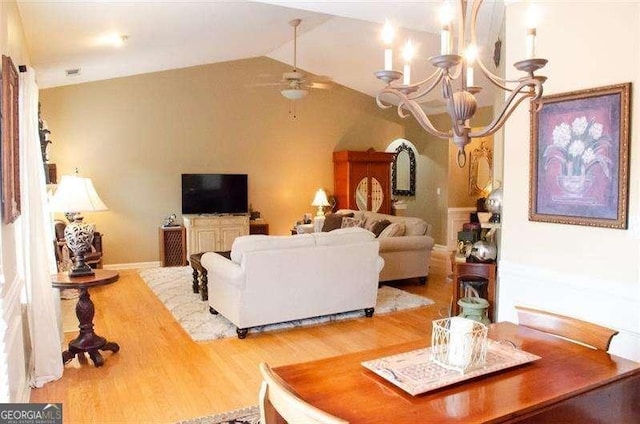 living room featuring wood-type flooring, ceiling fan with notable chandelier, and vaulted ceiling