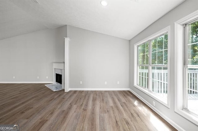 unfurnished living room with hardwood / wood-style floors, lofted ceiling, and a premium fireplace