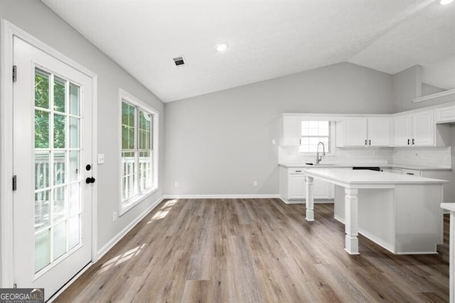 kitchen with backsplash, white cabinets, sink, vaulted ceiling, and a breakfast bar area