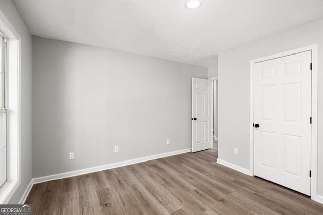 unfurnished bedroom with hardwood / wood-style floors and multiple windows