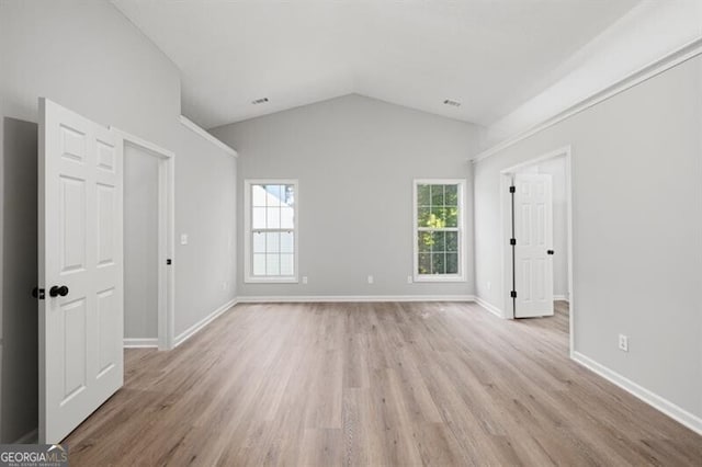 spare room with vaulted ceiling and light wood-type flooring